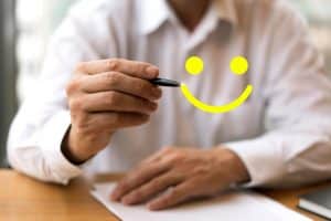 Homem de roupa social fazendo desenho de rosto feliz.