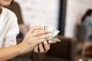 Mulher sentada no sofá contando dinheiro em espécie.