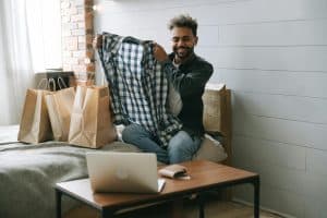 homem sorrindo com uma camisa xadrez nas mãos