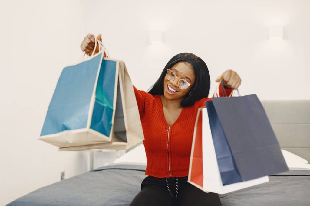 uma mulher sorrindo com sacolas de compras nas mão